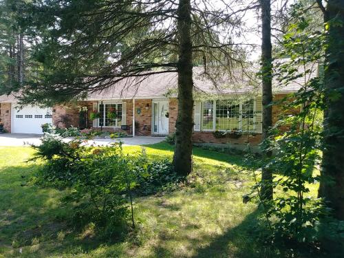 a brick house with trees in the yard at Andante Gîte Bed and Breakfast in Cantley