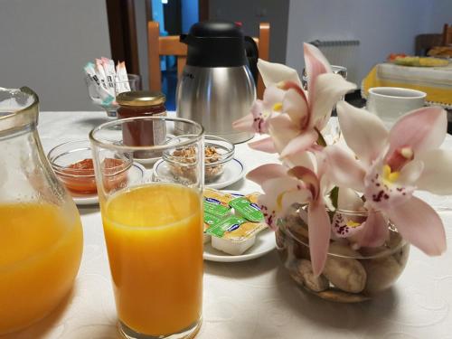 a table with a glass of orange juice and a bowl of flowers at Casa dos Tios in Fátima