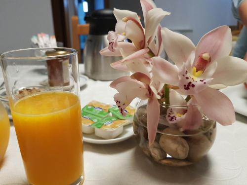 a vase of flowers next to a glass of orange juice at Casa dos Tios in Fátima