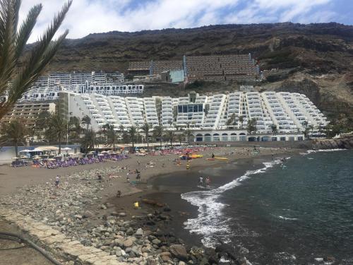 a large hotel on a beach with people on the beach at Private apartment with stunning ocean views and sunset. in Taurito