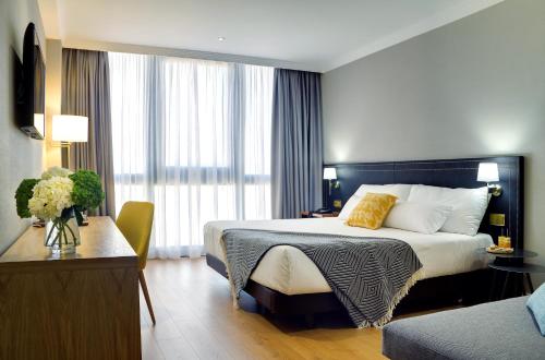 a hotel room with a large bed and a table at Oca Puerta del Camino Hotel in Santiago de Compostela