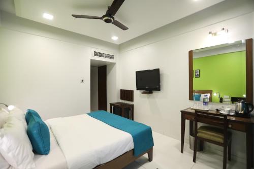 a bedroom with a bed and a desk and a television at Citizen Hotel in Mumbai