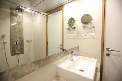 a bathroom with a sink and a shower and a mirror at Citizen Hotel in Mumbai