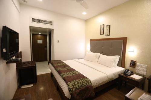a hotel room with a bed and a flat screen tv at Citizen Hotel in Mumbai