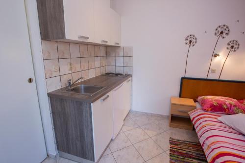 a small kitchen with a sink and a bed at Apartments Goga in Mali Lošinj