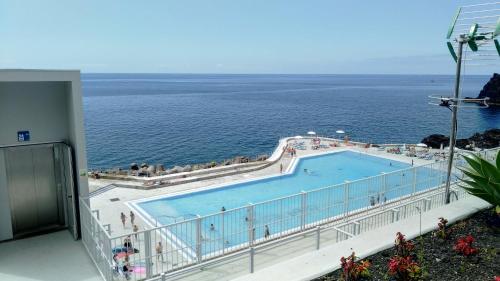 a swimming pool with the ocean in the background at Jardins Piornais Funchal Apartment in Funchal
