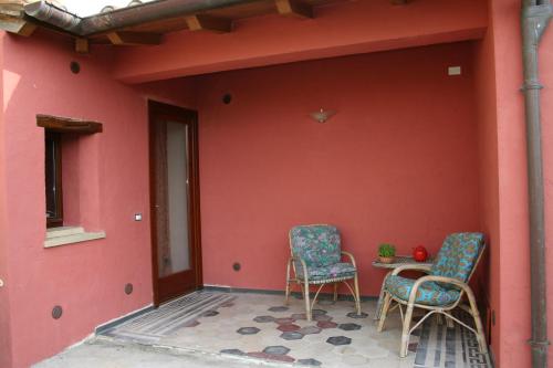 two chairs and a table on a red wall at Sa Domu de sa Contissa in Sèlegas
