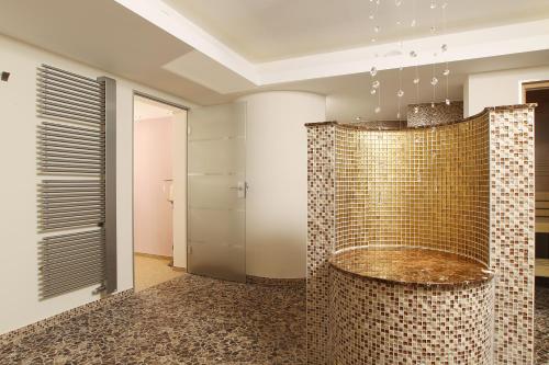 a bathroom with a shower with gold tiles at Hotel Seelust in Cuxhaven