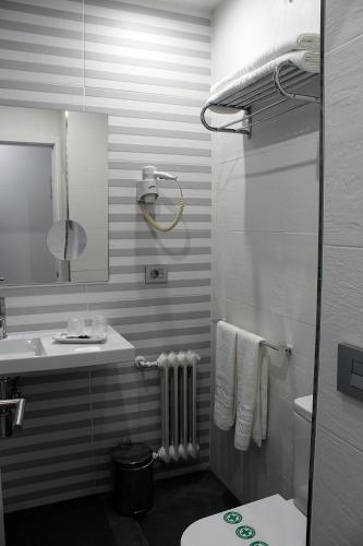 a bathroom with a sink and a toilet and a mirror at Hotel Altiana in Ourense