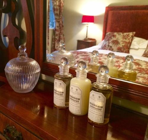 a group of three bottles on a table with a bed at Hurstwood Hall in Burnley