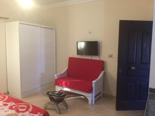 a red chair in a room with a tv on the wall at Nour Plaza Hurghada Studio Sea view in Hurghada