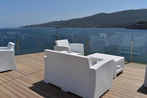a deck with white chairs and a view of the city at New Aegli Resort Hotel in Poros