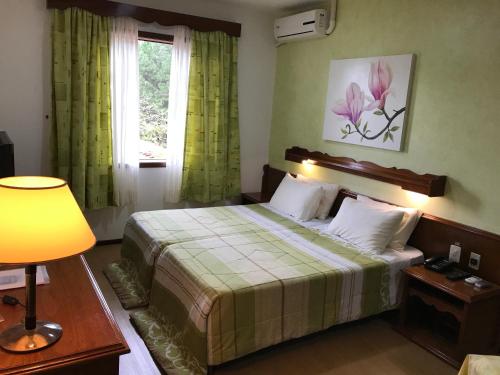 een slaapkamer met een bed met groene gordijnen en een raam bij Hotel Bergblick in Pomerode