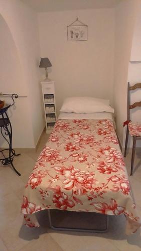 a bedroom with a bed with a flowered blanket on it at Giardino Segreto in Putignano