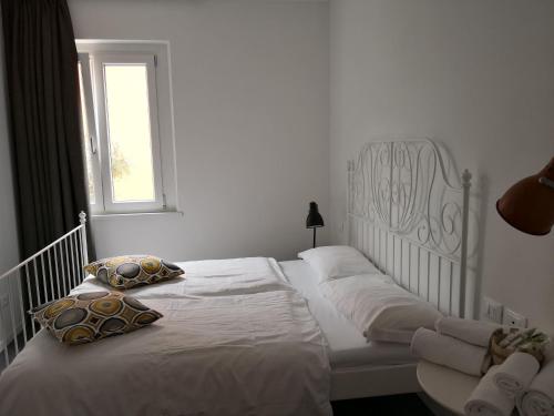a bedroom with a white bed with pillows and a window at Hotel Villa Rina in Riva del Garda