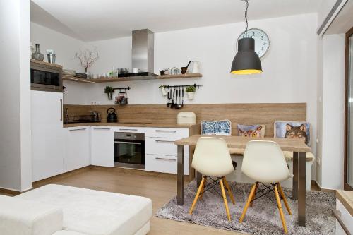 a kitchen with a wooden table and two white chairs at Apartmán Chopok Juh Nadia in Horná Lehota