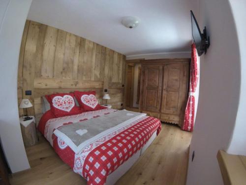 Un dormitorio con una cama roja y blanca y paredes de madera. en Berlot, en Morgex