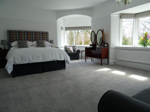 a bedroom with a bed and a chair and windows at Grendon Bed & Breakfast in Buxton