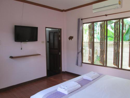a bedroom with a bed and a tv and a window at Asiana House in Khao Lak