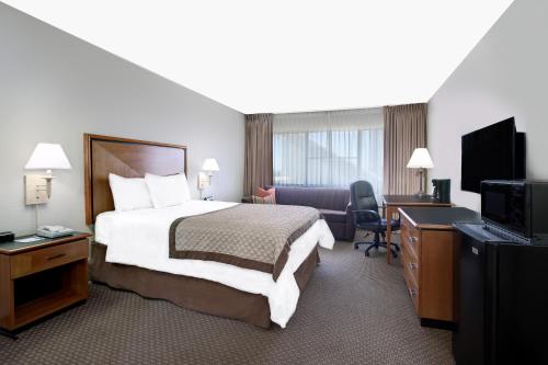 a hotel room with a bed and a desk and a television at Value Suites Extended Stay - Arlington in Arlington