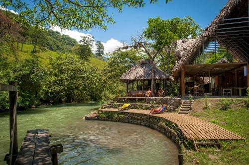 a person sitting on a bridge over a river at El Retiro Lanquin in Lanquín