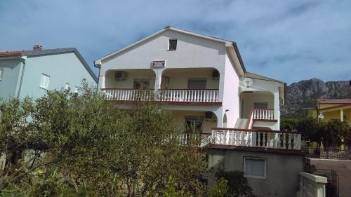 Casa blanca con balcón y montañas de fondo en Guesthouse BILI, en Karlobag