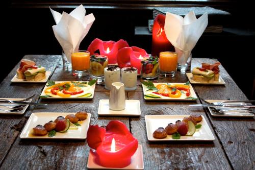 een houten tafel met borden eten en kaarsen bij Guest House Nuit Blanche in Brugge