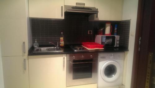 a kitchen with a sink and a washing machine at Residence Folla in Sousse