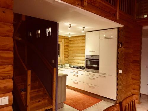 una cucina con mobili bianchi e una scala in una cabina di Romantic Cottage House a Žužemberk