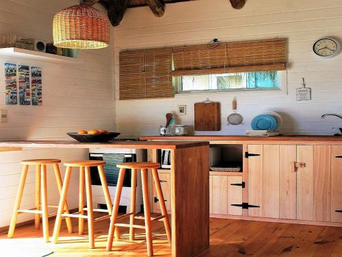 una cucina con sgabelli da bar in legno e un bancone di Cabaña PRAIA a Punta Del Diablo