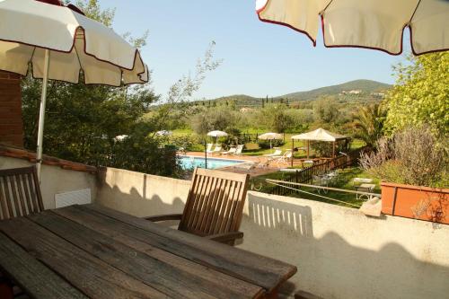 a wooden table with chairs and an umbrella and a pool at Casale Vigna Carbona in Gavorrano