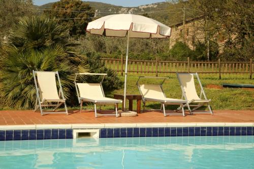 three chairs and an umbrella next to a pool at Casale Vigna Carbona in Gavorrano