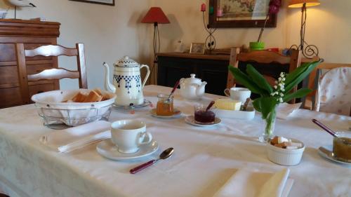 a table with a white table cloth with cups and dishes at Manoir de la Ville Marie in Hirel