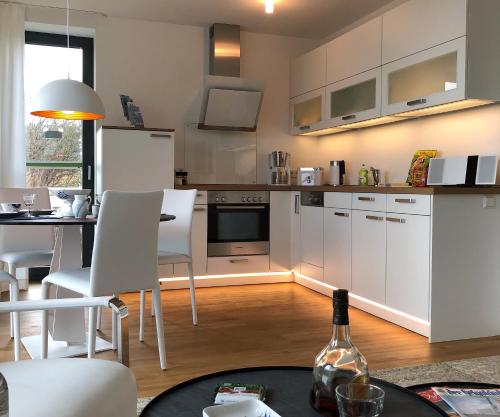 a kitchen with white cabinets and a table with a bottle of wine at Tor zum Meer in Helgoland