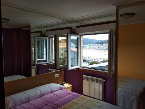 1 dormitorio con cama y ventana grande en Hostal Residencia Bahía, en Laxe