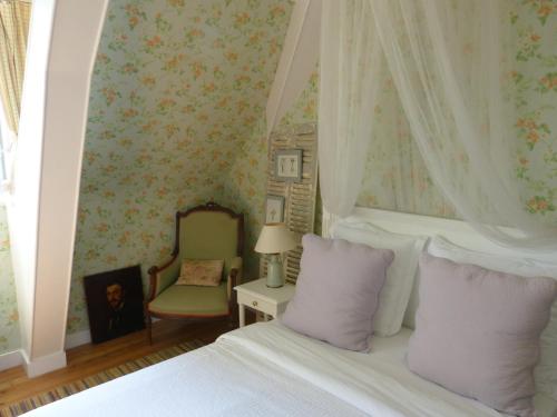 Un dormitorio con una cama con almohadas moradas y una silla en La Liniere, en Honfleur