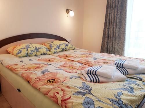 a bed with a floral comforter and pillows on it at Laimos vila in Palanga