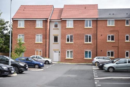 a large brick building with cars parked in a parking lot at Smartrips Apartments in Coventry