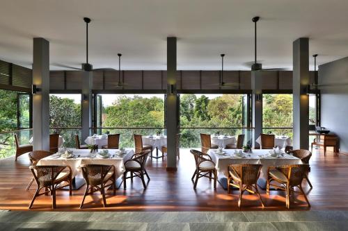 a dining room with tables and chairs and large windows at Ambong Pool Villas - Private Pool in Pantai Cenang