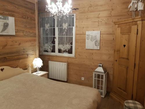 a bedroom with wooden walls and a bed and a chandelier at La petite chaumiere in Saint-Maurice-sur-Moselle