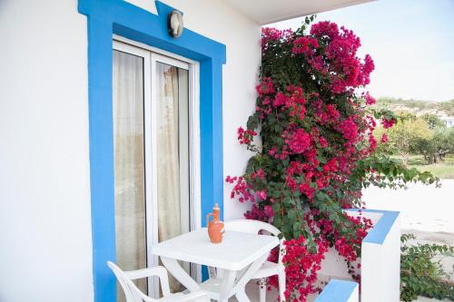 a table and chairs on a balcony with pink flowers at Matina Studios in Kefalos