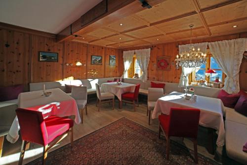 a restaurant with two tables and chairs and a chandelier at Landgut Thalerhof in Telfes im Stubai