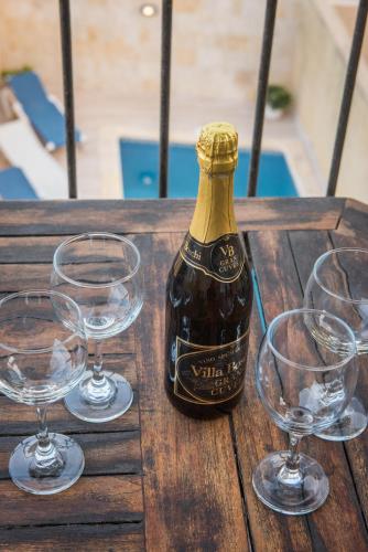 a bottle of wine and three wine glasses on a wooden table at Ta' Giga in Għarb
