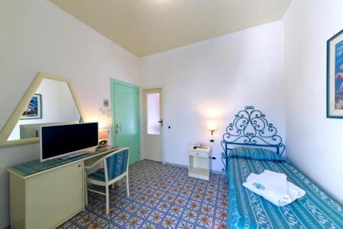 a bedroom with a bed and a desk with a computer at Hotel Villa Bianca in Ischia