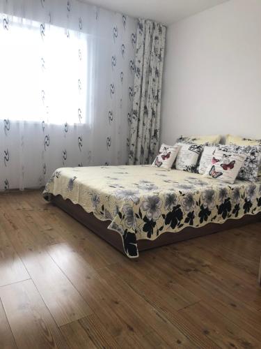 a bedroom with a bed with a floral bedspread and a window at Apartament Bella in Jurilovca