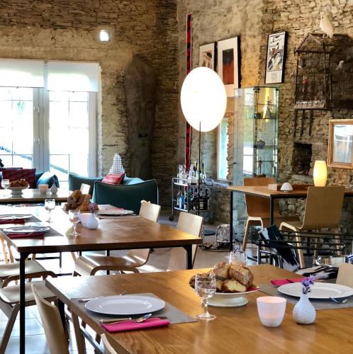 un restaurant avec des tables et des chaises en bois et une salle avec des fenêtres dans l'établissement Les Rochers, à Cerisy-la-Forêt