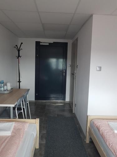 a room with two beds and a table and a door at Noclegi u Andrzeja in Gdańsk