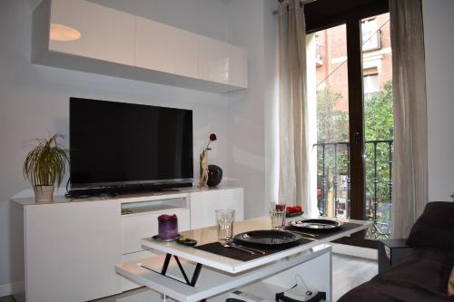 ein Wohnzimmer mit einem TV an einer weißen Wand in der Unterkunft Moderno apart centro in Madrid