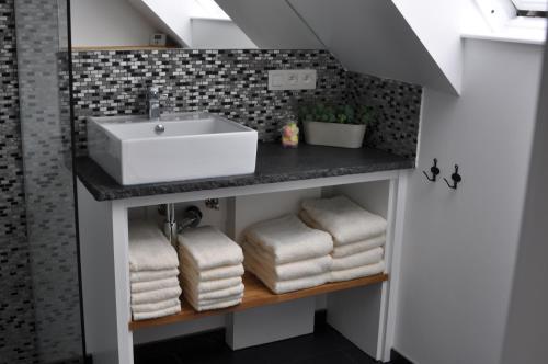 La salle de bains est pourvue d'un lavabo et de serviettes sur une étagère. dans l'établissement Casa-Anja, à Zingem