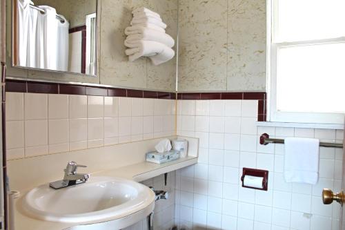 a bathroom with a sink and a toilet and towels at Budget Host Crestview Inn in Sault Ste. Marie